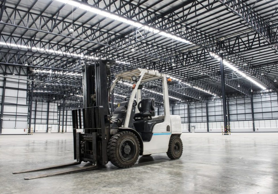 A white forklift inside an empty warehouse